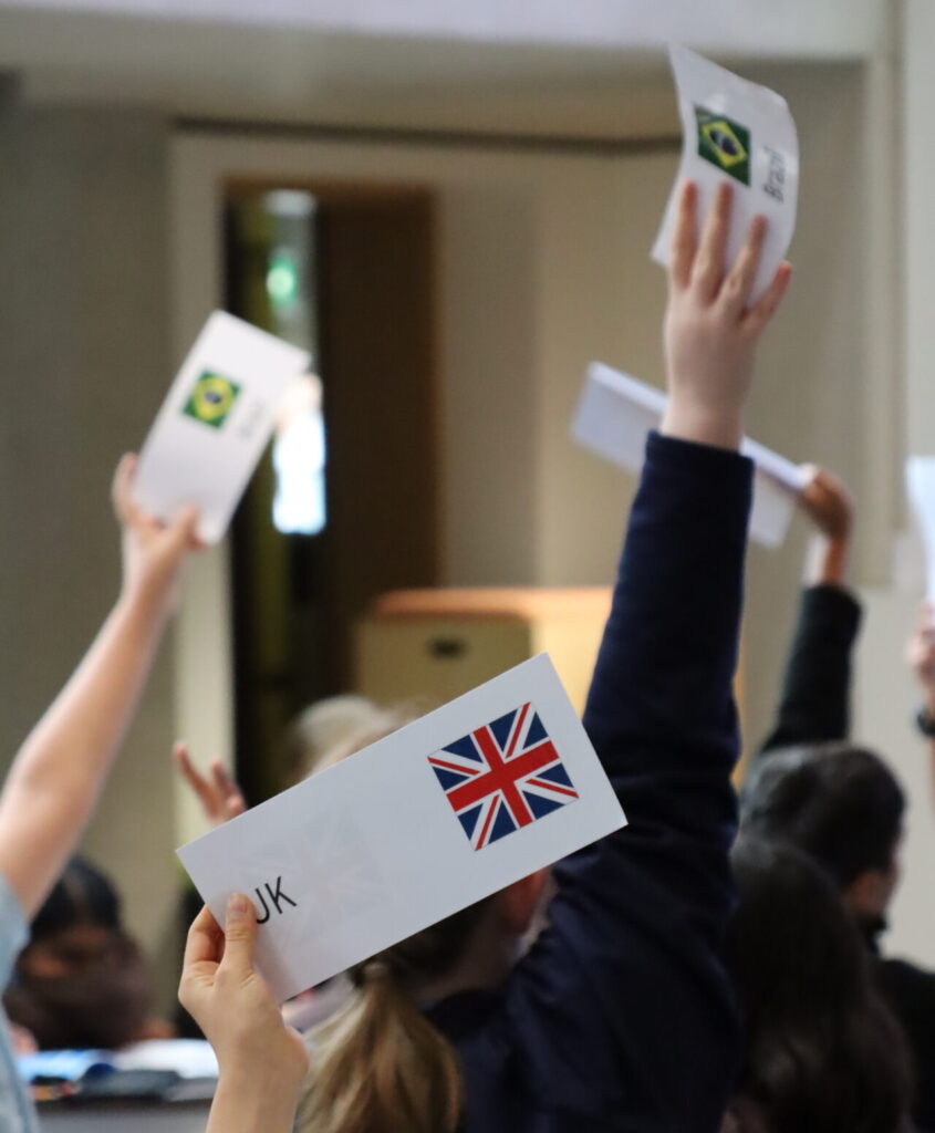 MUN Delegates raising their country flags in a pitch to raise a point during the conference